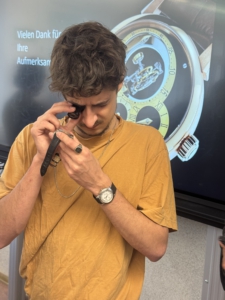Schüler betrachtet mit der Lupe eine Armbanduhr.